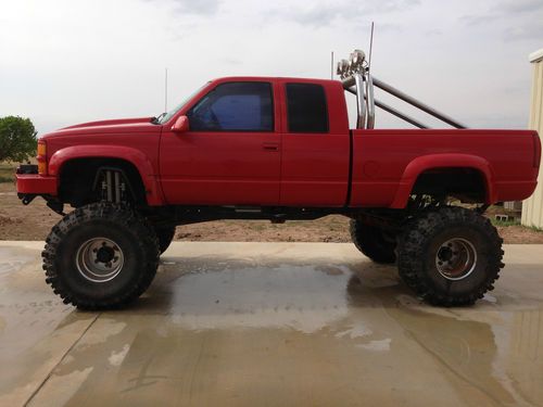 1997 red chevrolet extended cab pickup with 22 inch lift and 44 inch boogers
